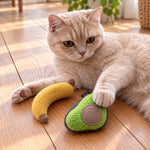 Cream cat pawing loose avocado and banana catnip toys